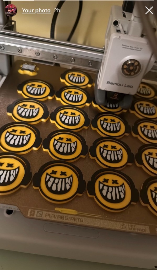 3D printer med tiskanjem serije rumenih emoji značk — AI generirani modeli v dejanski produkciji v delavnici 3DShop.si